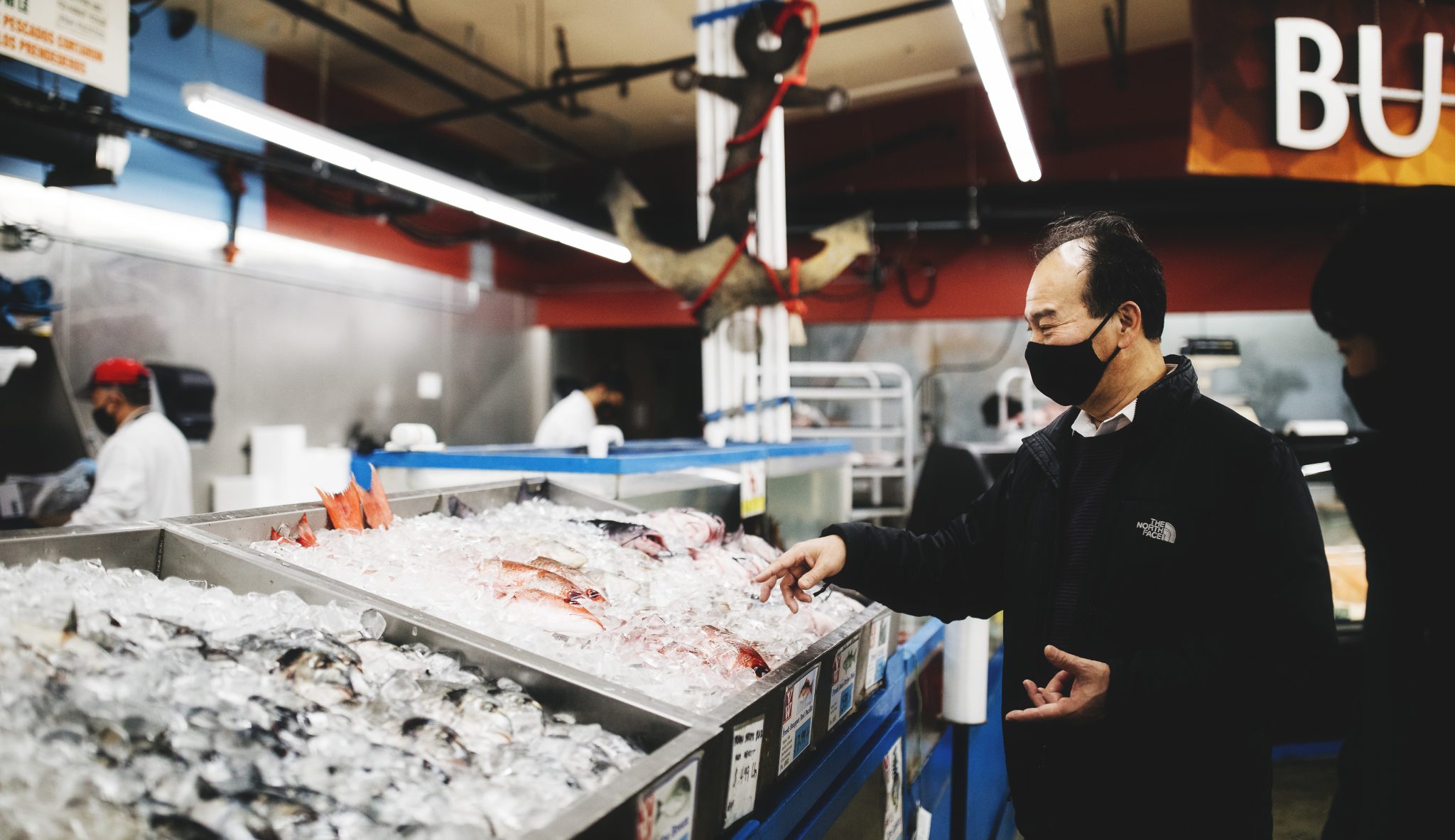 Man stands over fish at local supermarket in Renton, Washington.